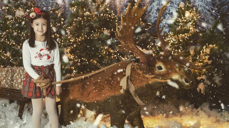 Niña junto a un reno en Navidad